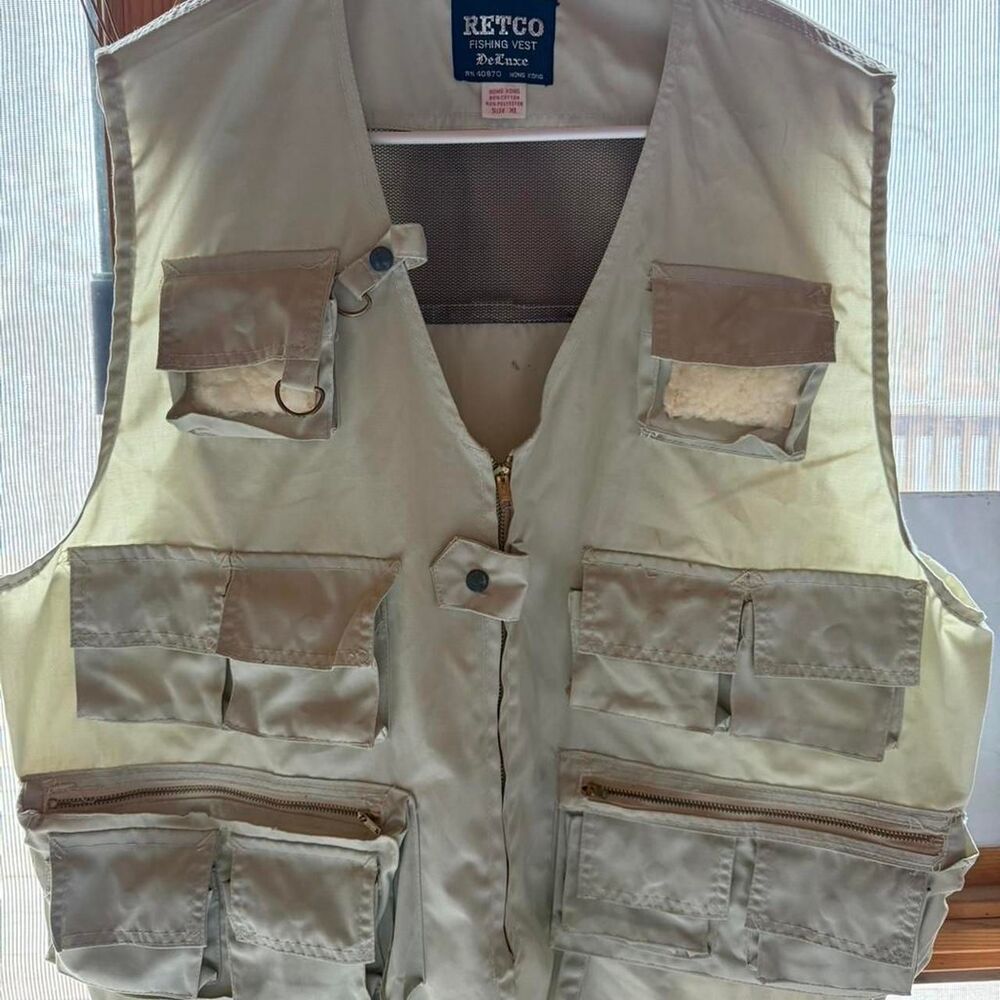 Tan fishing vest with multiple pockets and zippers. Size: XL